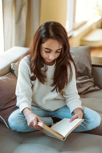 Foto niña leyendo en casa mientras está en cuarentena