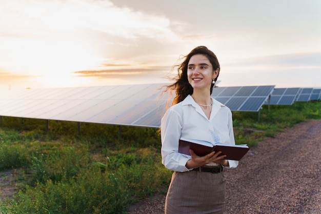 Niña leyendo cerca de filas de paneles solares en el suelo