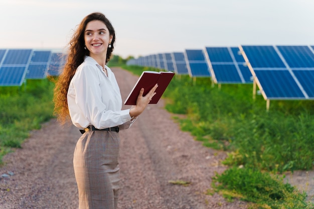 Niña leyendo entre dos filas de paneles solares en el suelo