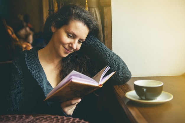 Foto la niña está leyendo un libro en un café.