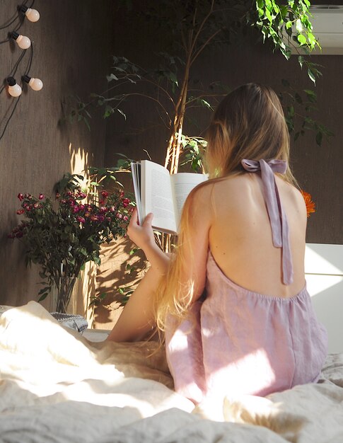 Foto niña leyendo un libro en la cama en pijama