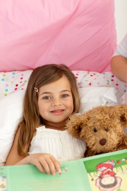 Niña leyendo un libro en la cama