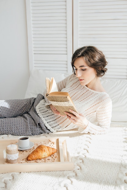 Niña leyendo un libro durante el desayuno