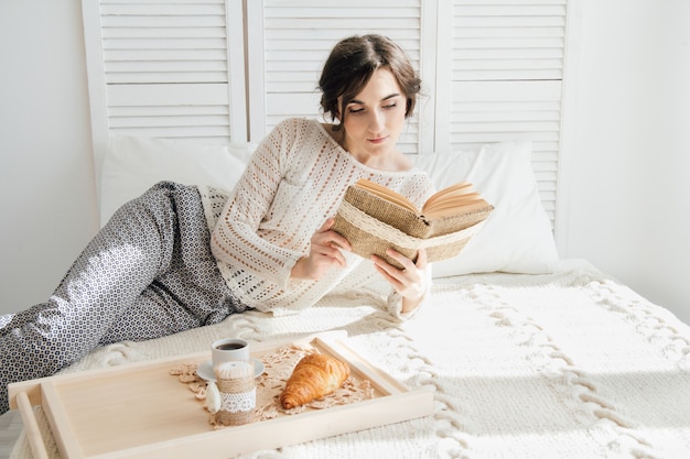 Niña leyendo un libro durante el desayuno