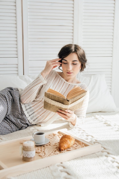 Niña leyendo un libro durante el desayuno