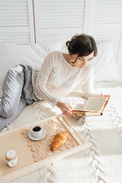 Niña leyendo un libro durante el desayuno