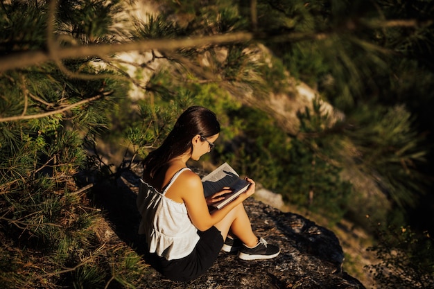 Niña leyendo un libro en la naturaleza durante el hermoso y tranquilo día de verano.