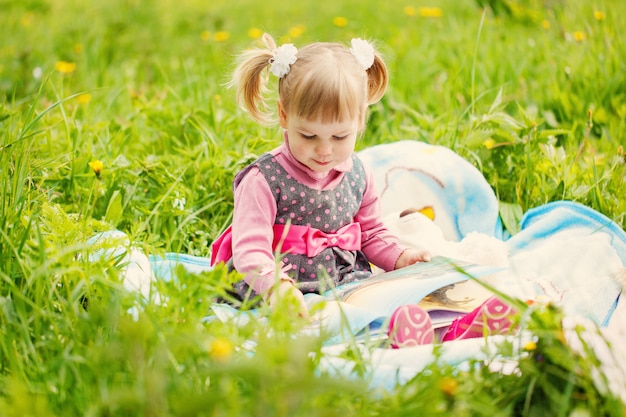 Niña leyendo un libro en el parque de verano