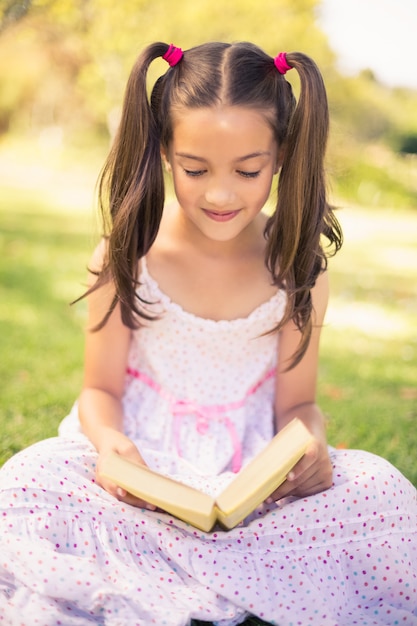 Niña leyendo un libro en el parque