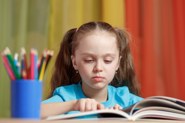 Foto niña está leyendo un libro sentado en una mesa