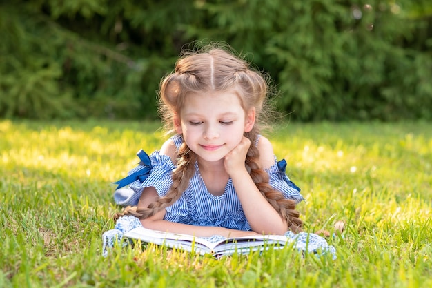 Una niña leyendo un libro sobre un césped verde
