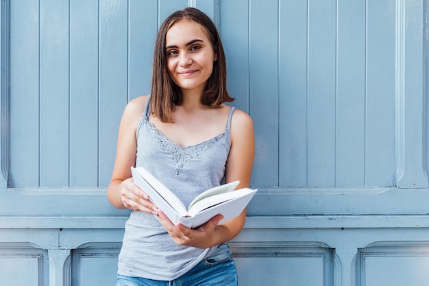 Foto niña leyendo un libro sobre fondo gris azul