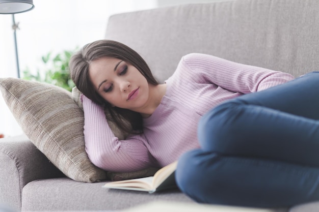 Niña leyendo un libro en el sofá