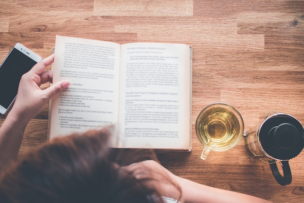 Foto una niña leyendo un libro con una taza de té y tetera