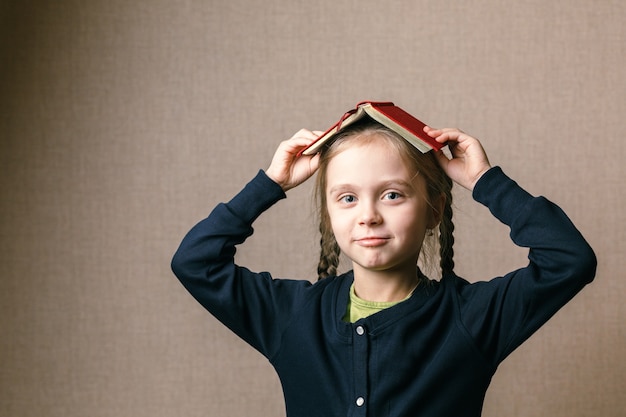 Foto niña con un libro sobre su cabeza