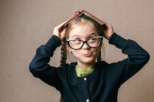 Foto niña con un libro sobre su cabeza