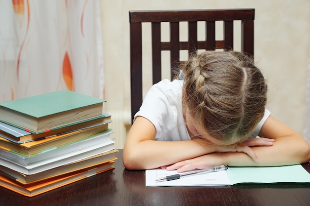 Niña con libros de texto estudiando dormido