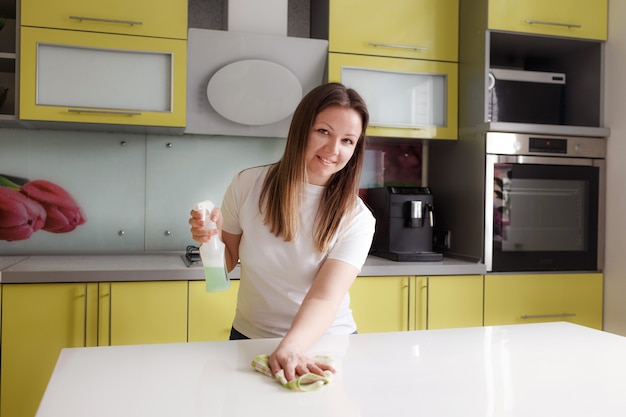 niña limpia la mesa de la cocina con un agente de limpieza