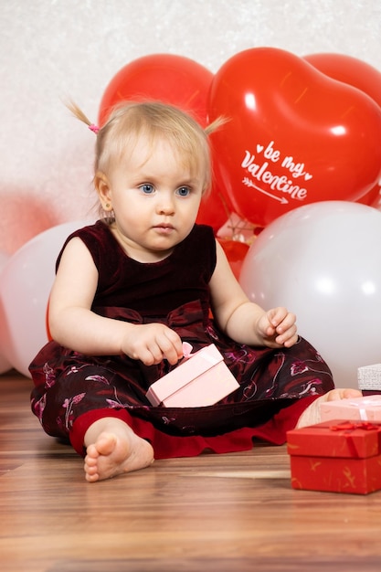 Niña linda abre regalos sentados entre las bolas