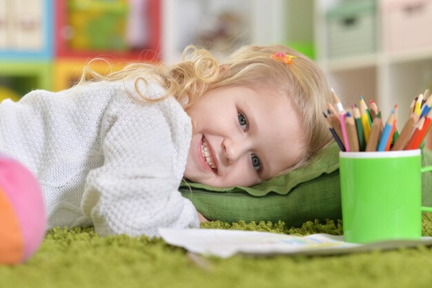 Niña linda acostada sobre una almohada en el suelo en casa