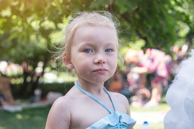 Niña linda con algodón de azúcar en el parque de la ciudad.