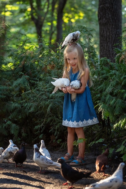 Niña linda alimentando palomas de sus manos