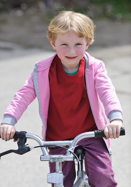 una niña linda aprende a conducir una bicicleta en un día soleado