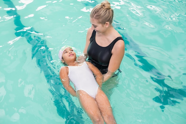 Niña linda aprendiendo a nadar con el entrenador