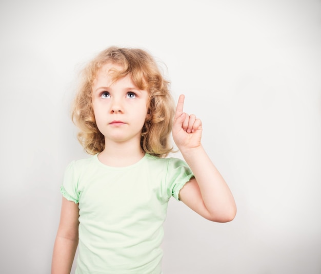 Niña linda apuntando hacia arriba, espacio de copia