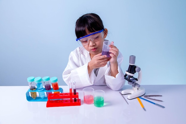 Niña linda asiática aprendiendo a un científico en el laboratorio de biología con equipo