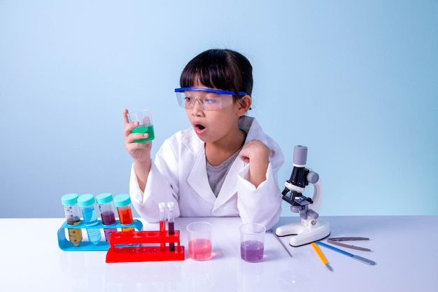 Niña linda asiática aprendiendo en el laboratorio de biología con equipo y mirando el microscopio. aprendiendo un