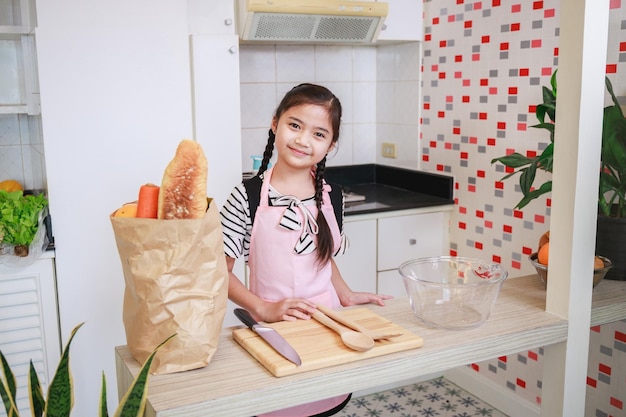 Niña linda asiática preparándose para cocinar en una cocina en casa Actividad de ocio