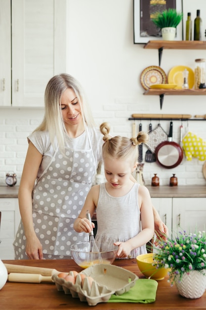 Niña linda ayuda a mamá a hornear galletas en la cocina. Familia feliz. Viraje.