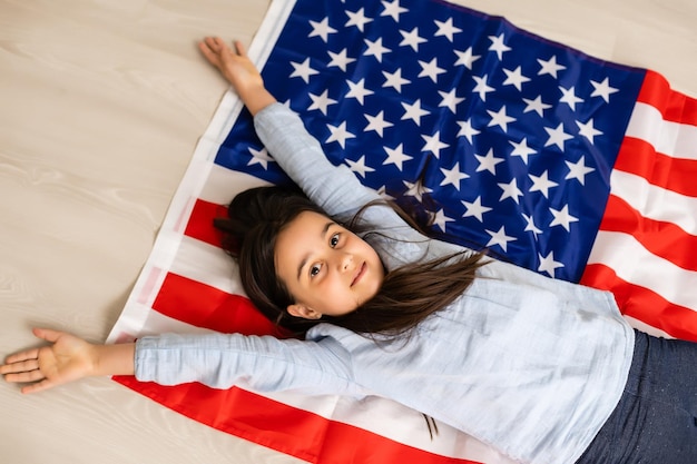 Foto niña linda y bandera de estados unidos en el fondo.