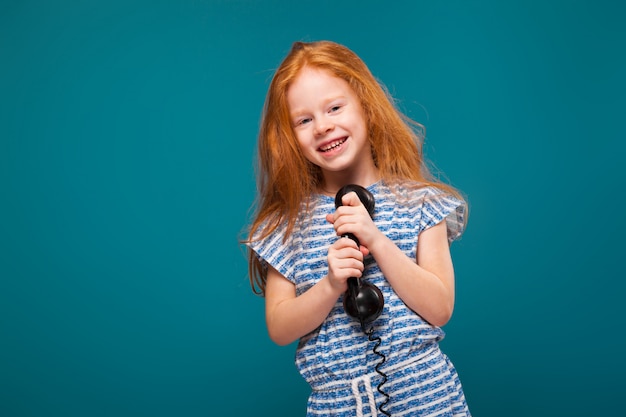 Foto niña linda de la belleza en camiseta con el pelo largo habla un teléfono