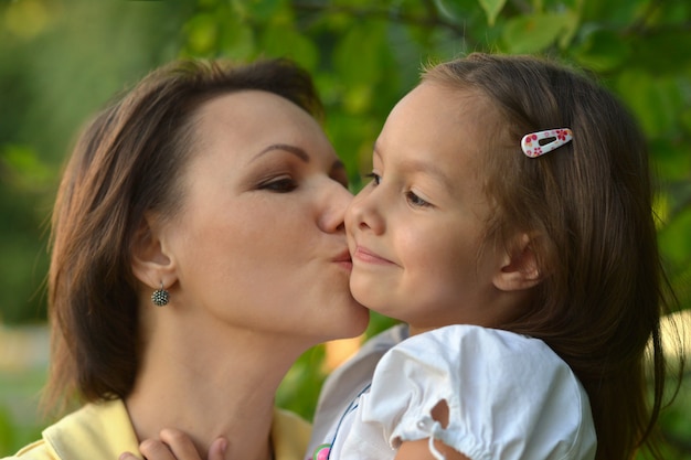 Niña linda besando a su madre en el parque