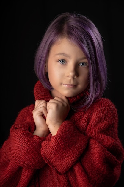 Niña linda con cabello morado en un suéter rojo