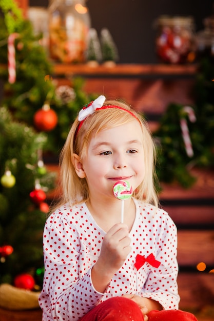 Niña linda con cabello rubio, ojos azules con dulces navideños