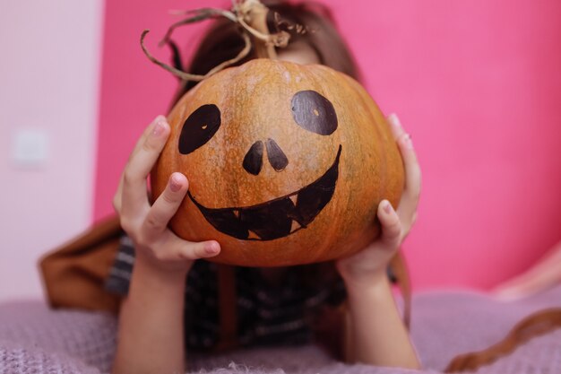 Niña linda con calabaza tallada en su habitación