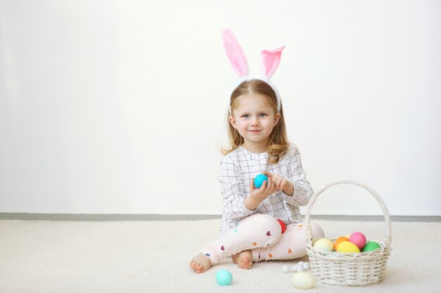 Niña linda con canasta de pascua sobre un fondo claro