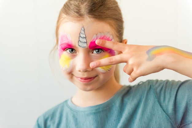 Foto niña linda caucásica con pintura de cara de unicornio