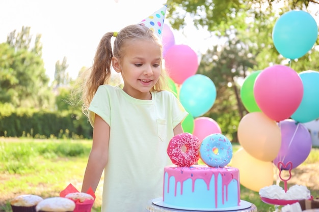 Niña linda celebrando cumpleaños al aire libre