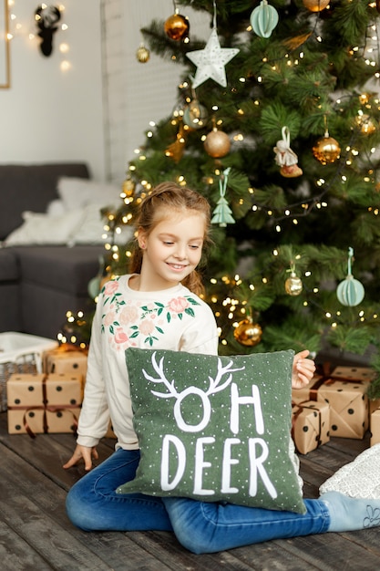 Niña linda cerca del árbol de navidad