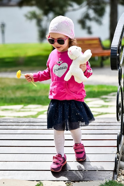 Una niña linda con una chaqueta rosa y un sombrero rosa camina por la ciudad Primavera soleada Infancia feliz