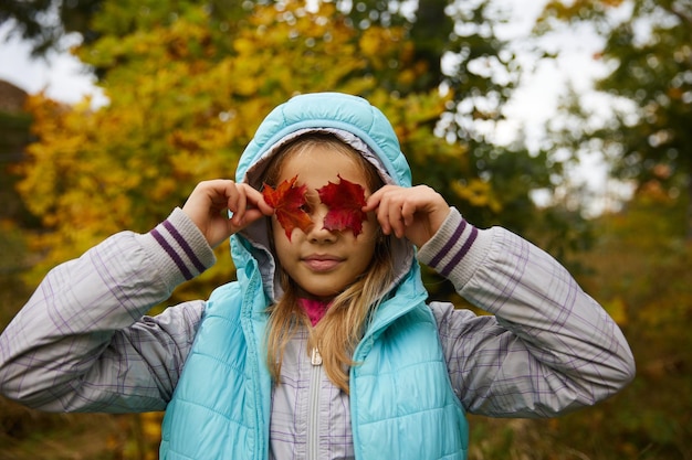 La niña linda cierra los ojos con hojas caídas brillantes