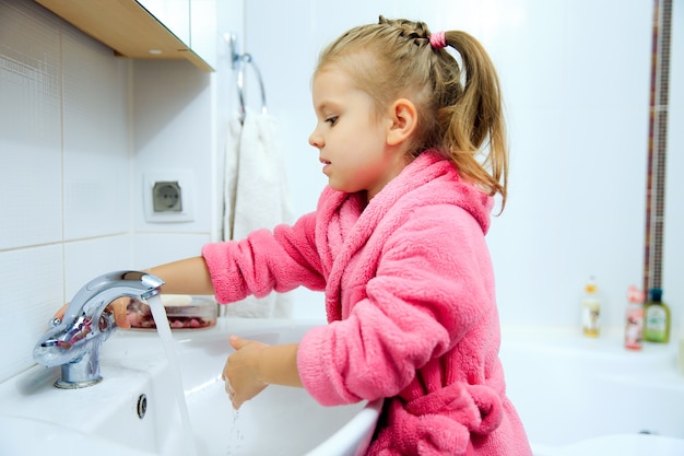 Niña linda con cola de caballo en bata de baño rosa