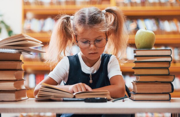 Niña linda con coletas está en la biblioteca