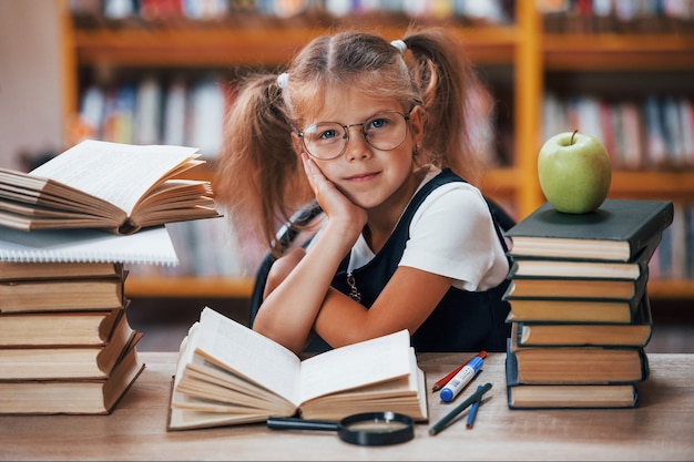 Niña linda con coletas está en la biblioteca