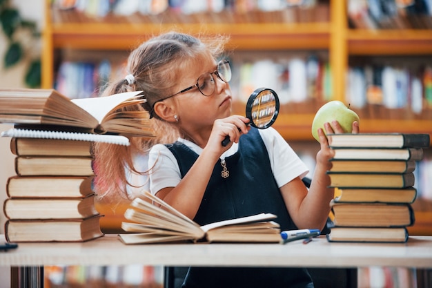 Niña linda con coletas está en la biblioteca