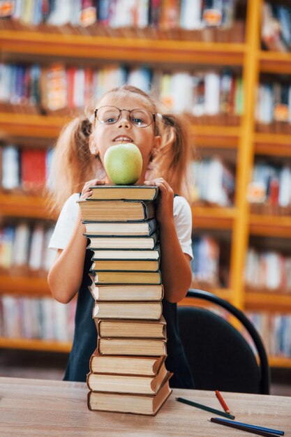 Niña linda con coletas está en la biblioteca